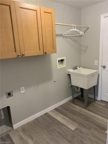 The laundry has storage cabinets, laundry sink, and a rod to hang clothes on.