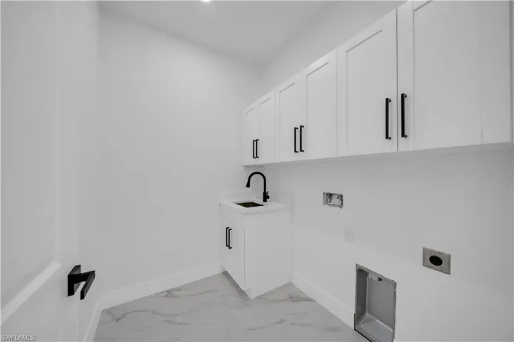 Washroom with cabinet space, light marble finish floors, hookup for a washing machine, and hookup for an electric dryer