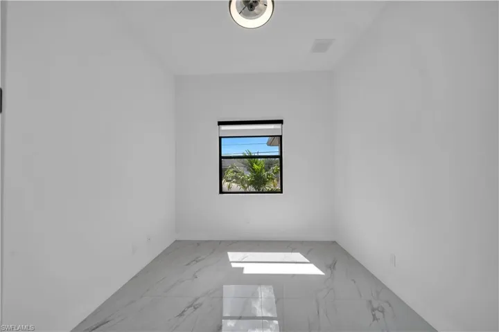 Empty room featuring marble look tiles and baseboards