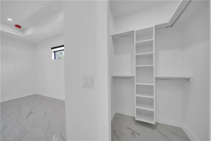 Walk in closet featuring light marble finish floors