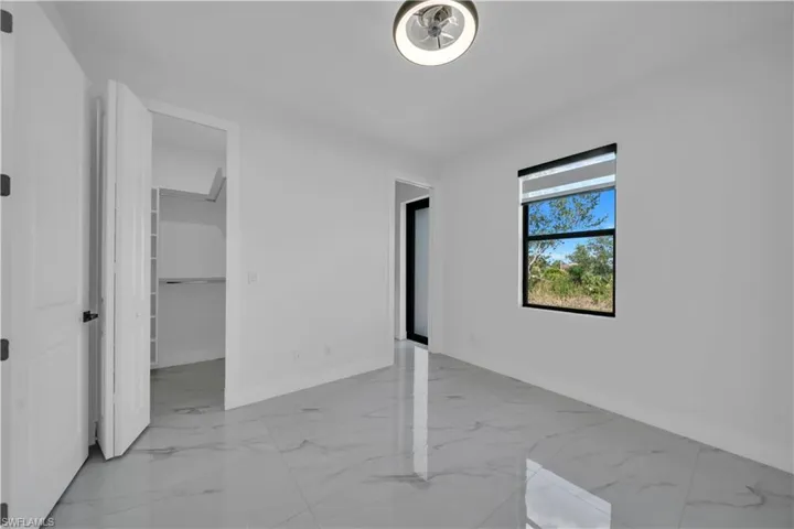 Unfurnished bedroom with light marble finish floors and a spacious closet