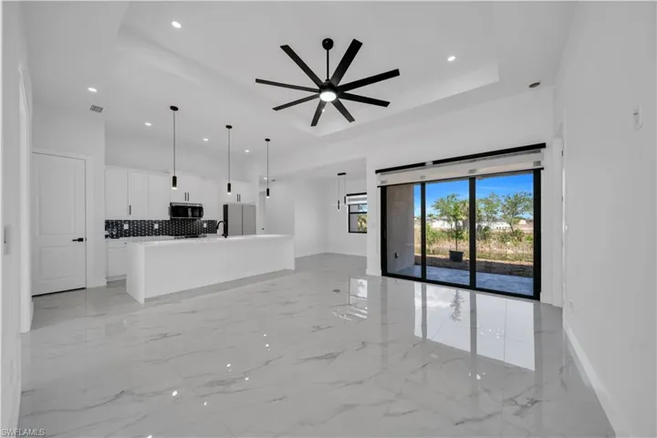 Unfurnished living room with light marble finish floors, a raised ceiling, recessed lighting, and ceiling fan