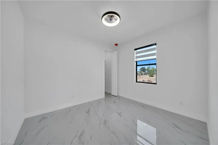 Spare room featuring marble look tiles and baseboards
