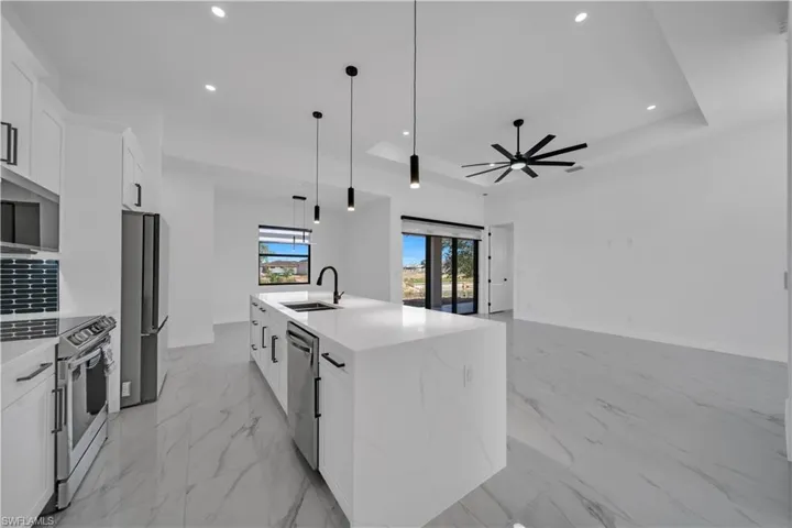 Kitchen with white cabinets, appliances with stainless steel finishes, light stone counters, recessed lighting, and open floor plan