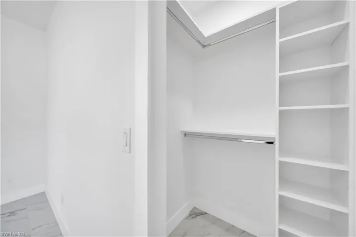 Walk in closet featuring light marble finish flooring