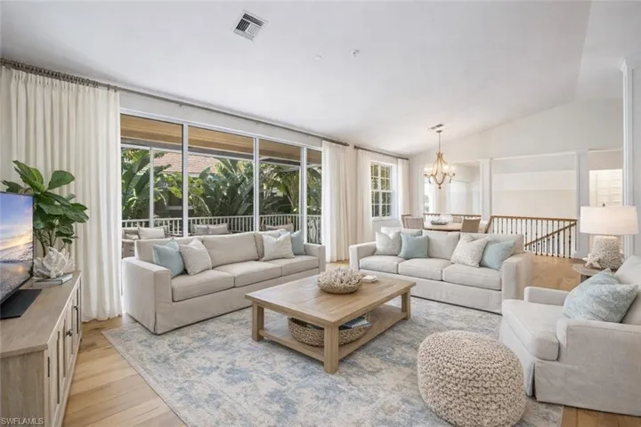 Living room featuring light wood finished floors, lofted ceiling, plenty of natural light, and a chandelier