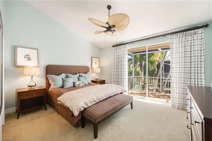 Carpeted bedroom with access to exterior, vaulted ceiling, and ceiling fan