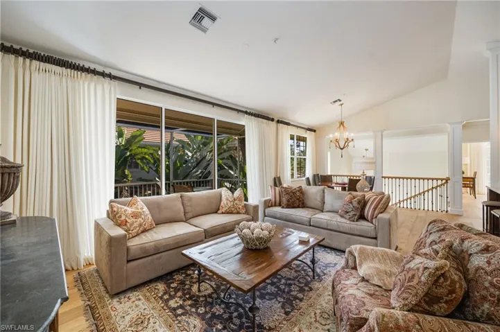 Living area featuring lofted ceiling, wood finished floors, and a chandelier