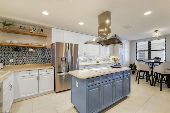 Kitchen featuring 42" white cabinetry, open shelves, stainless steel appliances, center island and pantry