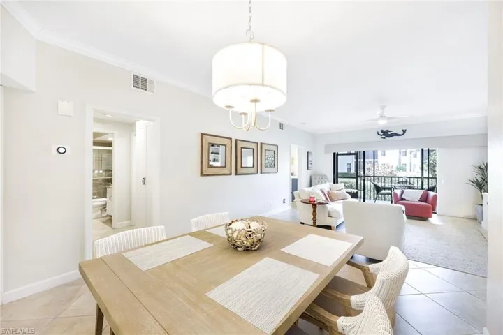Tiled dining area featuring ceiling fan and crown molding