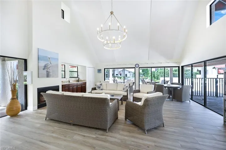 Living room with light hardwood / wood-style floors, an inviting chandelier, and a towering ceiling