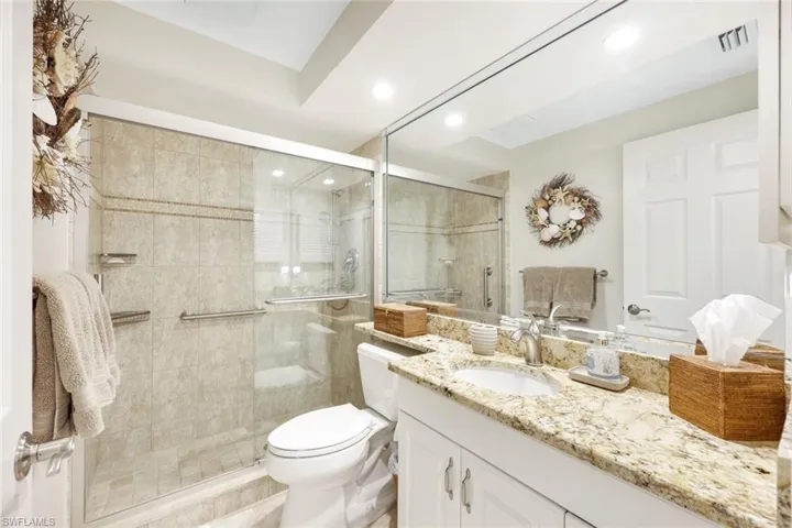 Bathroom with a shower with door, toilet, and vanity