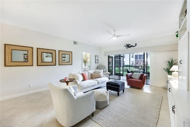 Living room featuring light tile patterned floors, ornamental molding, and ceiling fan
