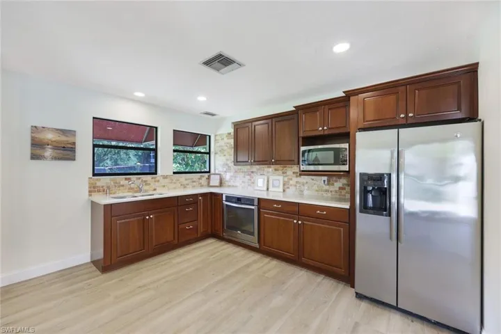 Kitchen with backsplash, sink, stainless steel appliances, and light hardwood / wood-style flooring