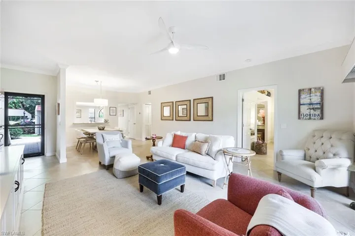 Tiled living room with ceiling fan and ornamental molding