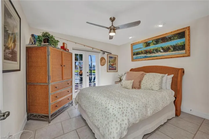 Bedroom featuring french doors, access to exterior, light tile patterned floors, and a ceiling fan