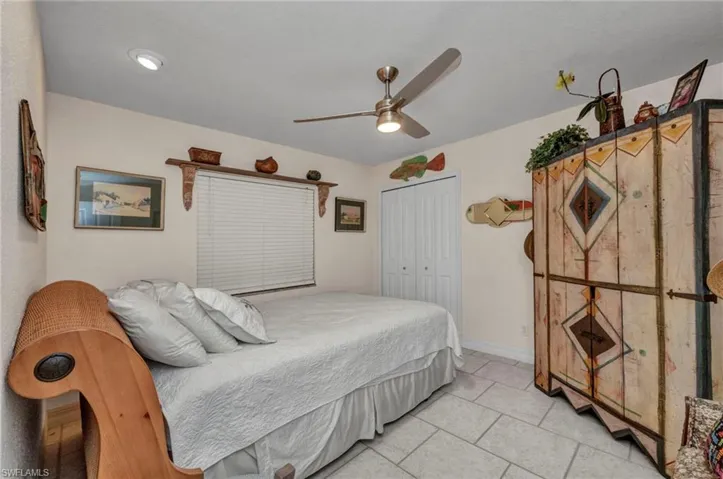 Bedroom with a closet, light tile patterned floors, and a ceiling fan