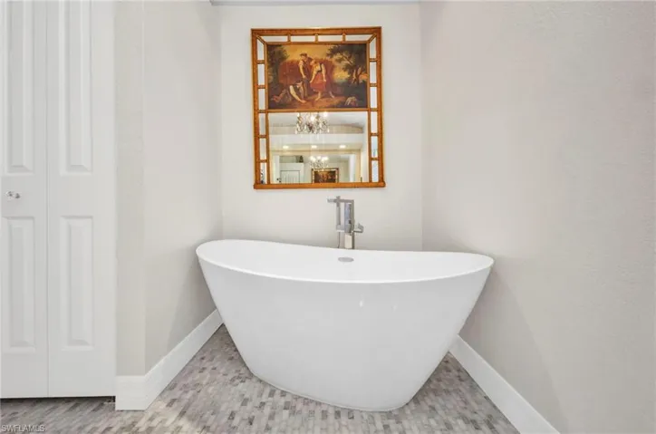 Bathroom featuring a soaking tub and baseboards
