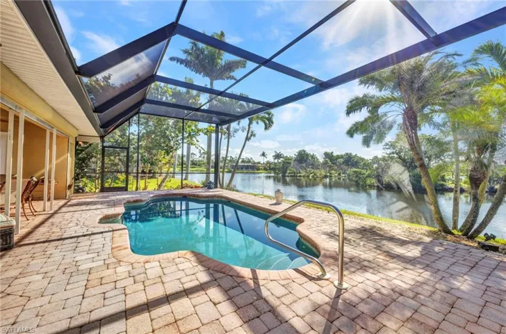 Swimming pool featuring a water view, a patio area, and glass enclosure