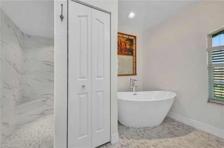 Full bathroom featuring a closet, a freestanding tub, a marble finish shower, and marble finish flooring