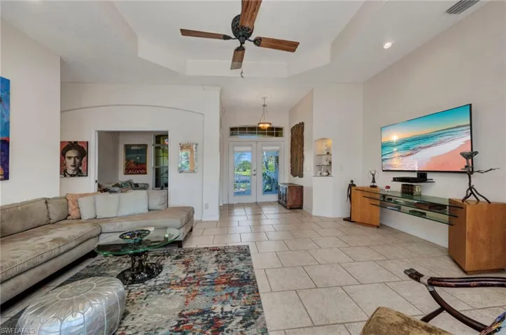 Living area with french doors, a tray ceiling, ceiling fan, and light tile patterned floors