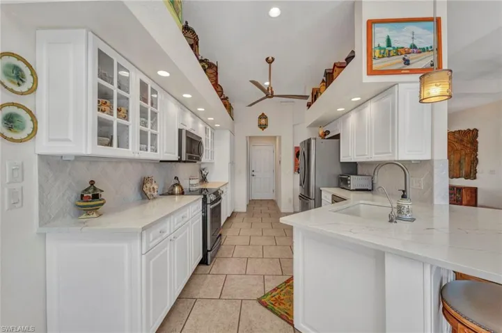 Kitchen featuring stainless steel appliances, decorative backsplash, white cabinets, a peninsula, and recessed lighting