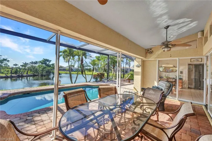 Sunroom / solarium with a ceiling fan, a pool, a water view, vaulted ceiling, and outdoor dining space
