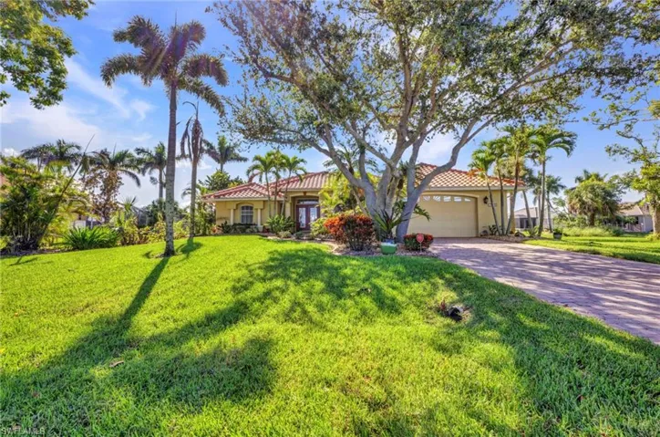 Mediterranean / spanish-style home with an attached garage, driveway, a tiled roof, and a front lawn