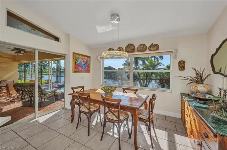 Dining space featuring a water view, a chandelier, light tile patterned flooring, and ceiling fan