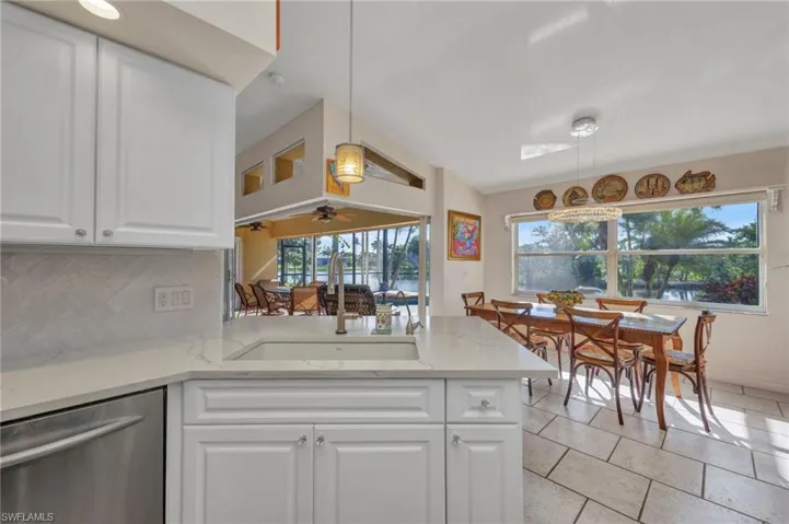 Kitchen featuring stainless steel dishwasher, plenty of natural light, white cabinets, and decorative backsplash