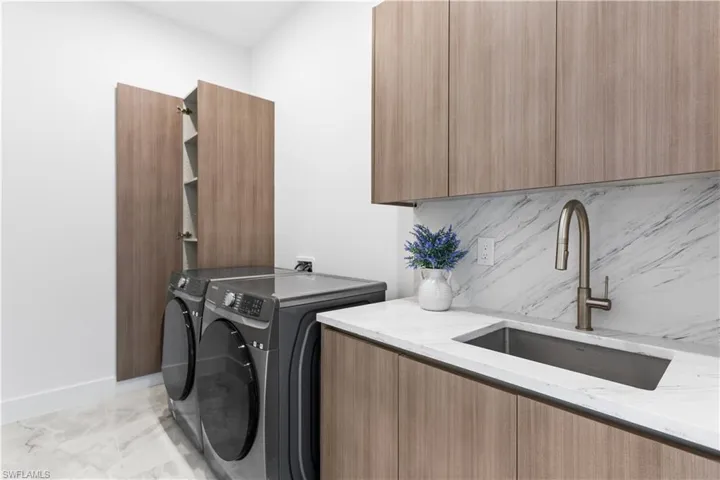 Custom built cabinets, SAMSUNG washer and dryer, laundry tub with full backsplash, and storage!