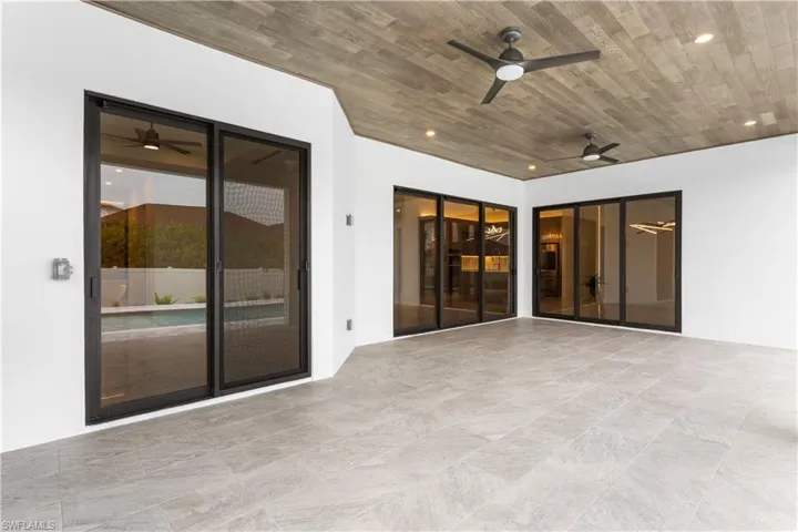 Expansive lanai with flat wooden ceiling and tile flooring with sliding doors to the dining room, living room, and master bedroom!