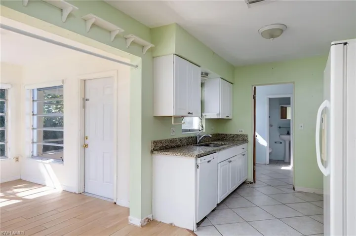 Kitchen featuring dark stone counters, white appliances, white cabinets, and light wood-type flooring