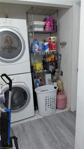 Clothes washing area with estacked washer and dryer and wood finished floors