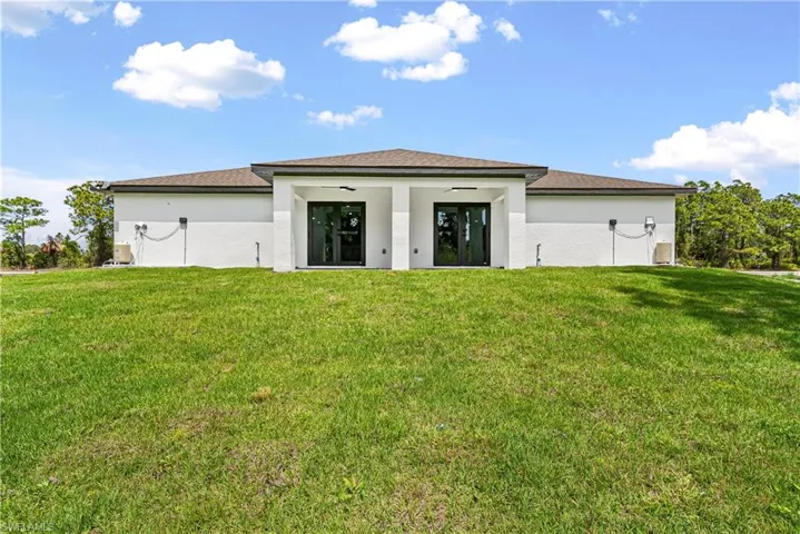 Rear view of house with a yard and stucco siding