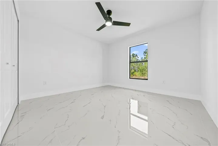 Unfurnished room featuring light marble finish floors and ceiling fan