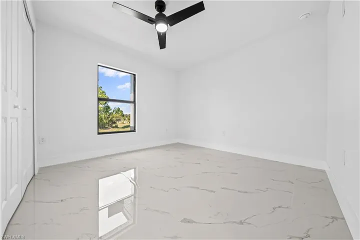 Unfurnished bedroom with ceiling fan and light marble finish flooring