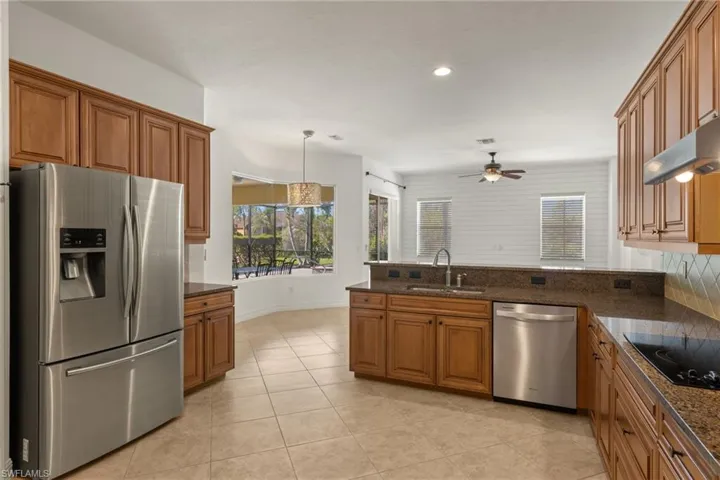 Kitchen featuring stainless steel appliances, brown cabinets, a ceiling fan, healthy amount of natural light, and recessed lighting