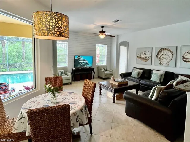 Living area with arched walkways, light tile patterned floors, and a ceiling fan