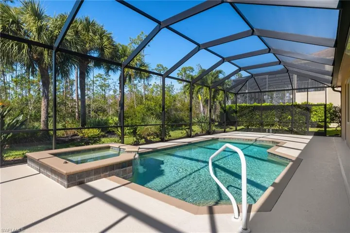 View of swimming pool with a pool with connected hot tub, a patio area, and glass enclosure
