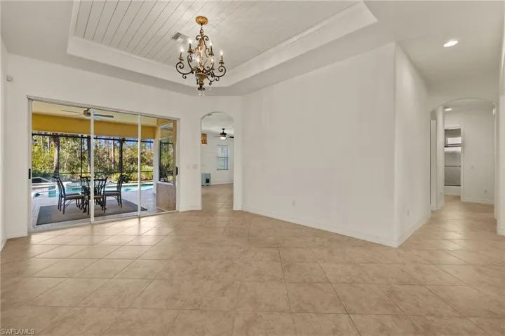 Unfurnished room with arched walkways, a tray ceiling, light tile patterned floors, crown molding, and recessed lighting