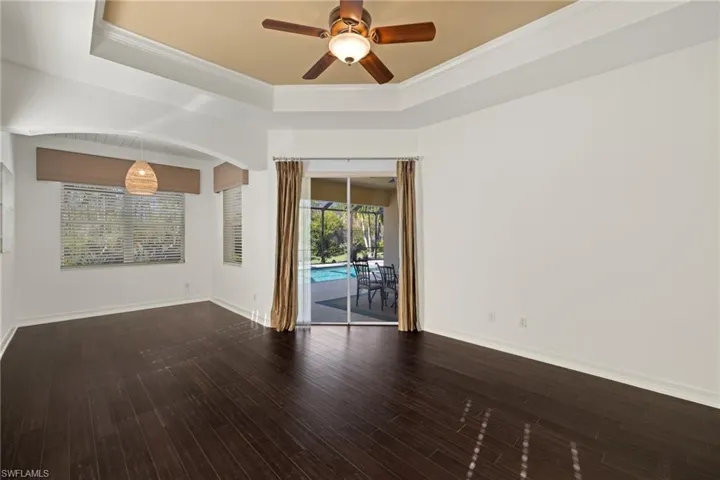 Unfurnished room with a tray ceiling, ceiling fan, wood finished floors, and crown molding