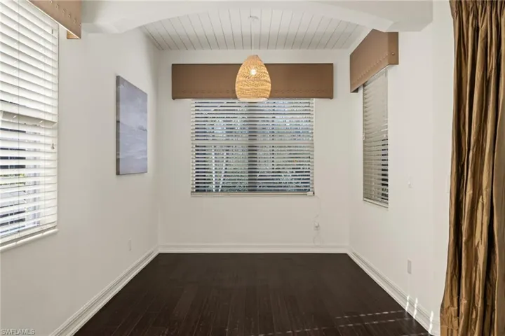 Empty room featuring dark wood finished floors, plenty of natural light, and a wood ceiling with exposed beams