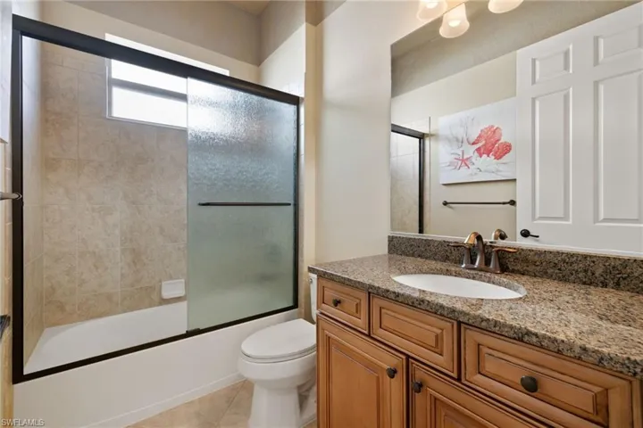 Full bath with vanity, bath / shower combo with glass door, and tile patterned flooring