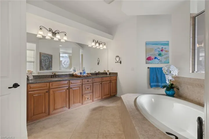 Full bathroom featuring a garden tub, double vanity, and tile patterned floors