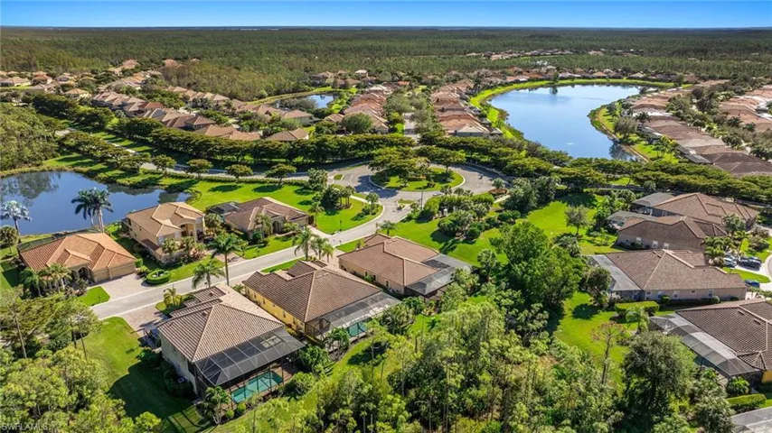 Aerial perspective of suburban area featuring a large body of water and a forest