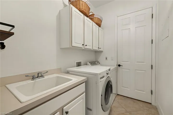 Washroom featuring separate washer and dryer, cabinet space, and light tile patterned floors