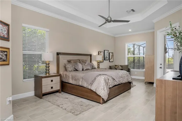 Owner suite is quite spacious, with high tray ceilings, decorative crown molding, designer ceiling fan, and private entry to outdoor living space. *Note that there is NO CARPET in this home... All porcelain tile on the lower level and hardwood flooring on the stairs and in the loft space.