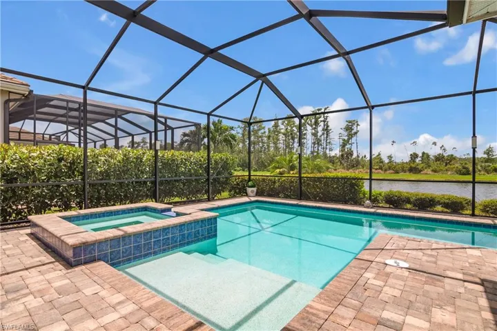 View of swimming pool with an in ground hot tub, a patio, and glass enclosure