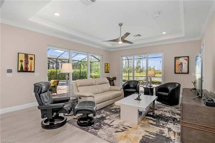 Great room features tray ceiling with crown molding and a seamless indoor/outdoor living space with plenty of sliders leading out to the oversized lanai and outdoor kitchen.